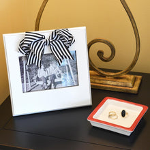 Load image into Gallery viewer, White frame with black &amp; white stripe bow at the top of the frame, holds 4 x 6 on a desk

