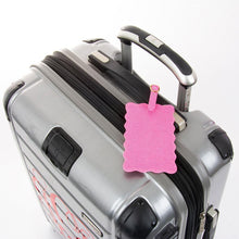 Load image into Gallery viewer, Lifestyle view of our Pink Lizard Scallop Luggage Tag
